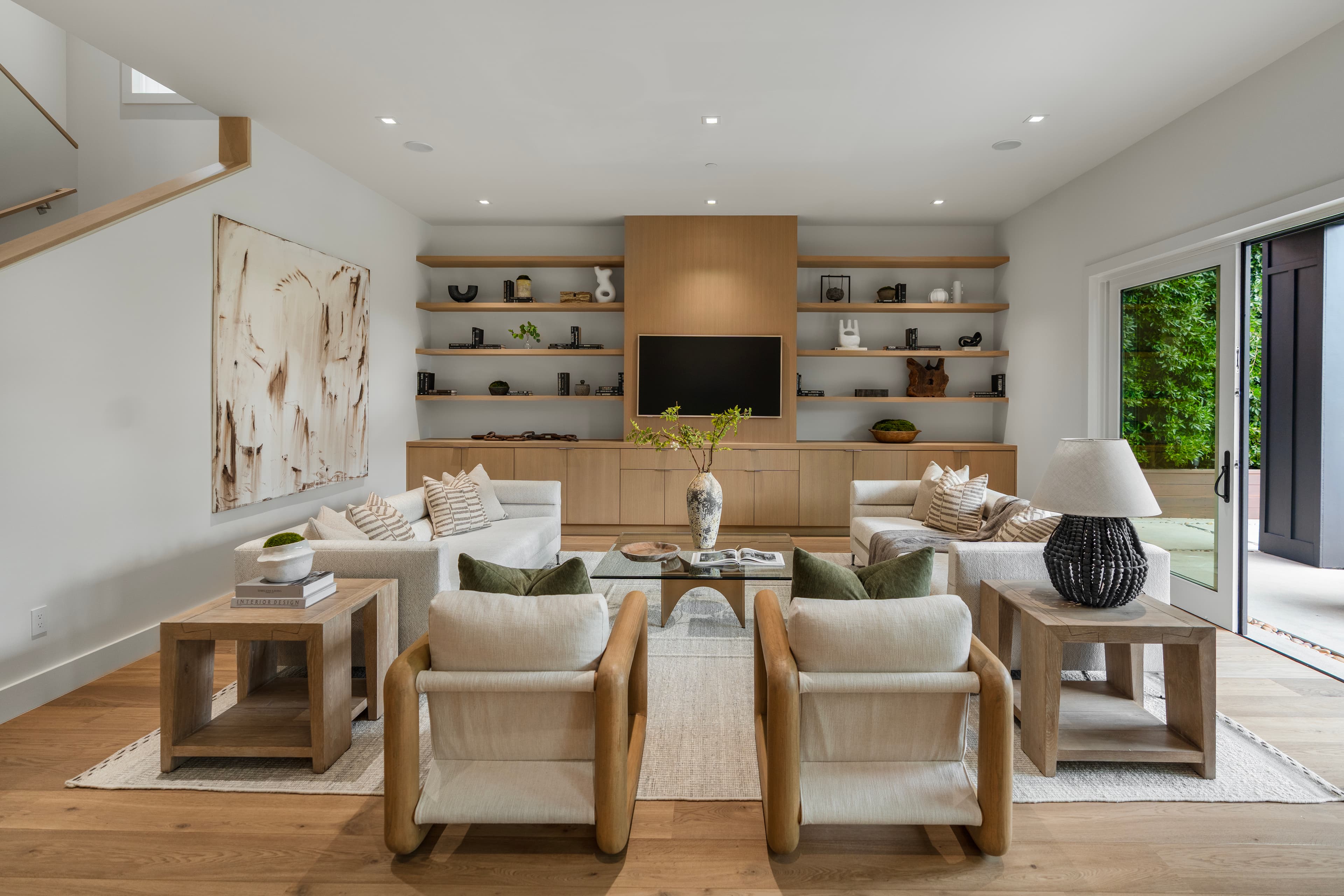 Modern living room with white sofas, wooden built-in TV unit, and abstract wall art.
