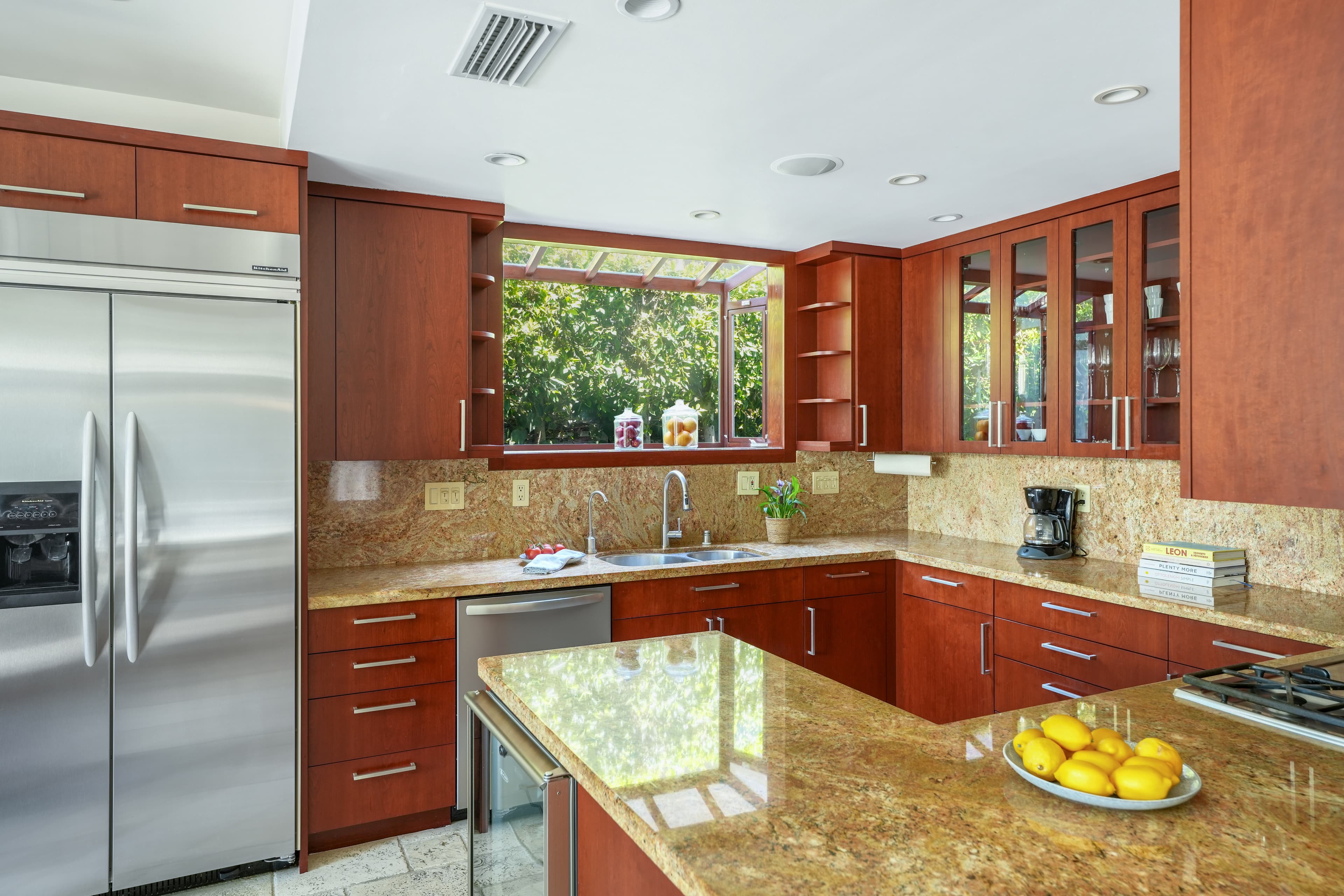 Modern kitchen featuring cherry wood cabinets, granite countertops, stainless steel appliances, and a garden window.